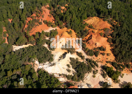 VUE AÉRIENNE.Carrière d'ocre rouge contrastant fortement avec le feuillage vert environnant.Rustrel, Lubéron, Vaucluse, Provence, France. Banque D'Images