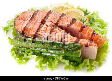 Pavé de saumon et asperges sur feuilles de laitue sur un fond blanc. Banque D'Images