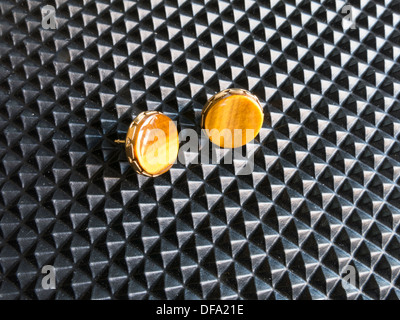 Still Life of Tiger's Eye Earrings sur fond noir texturé Banque D'Images