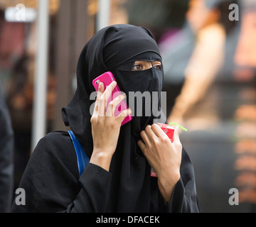 Femme musulmane portant le niqab on mobile phone Banque D'Images