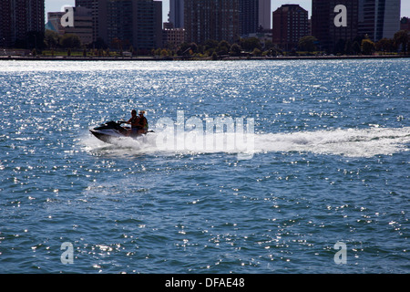 Detroit, Michigan - un couple monte un jet ski sur la rivière Détroit. Dans l'arrière-plan est Windsor (Ontario). Banque D'Images