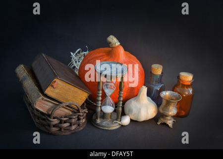 Livres de magie en vintage panier, hourglass, halloween citrouille et l'ail dans une pièce sombre Banque D'Images