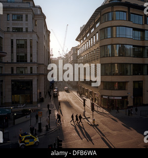 Trois affaires marcher sur une jonction en fin d'après-midi du soleil dans une rue de la ville de Londres, au cœur de la capitale, le quartier financier. Banque D'Images