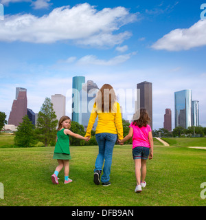 La mère et les filles marcher main dans la main sur les toits de la ville moderne sur la pelouse verte du parc Banque D'Images