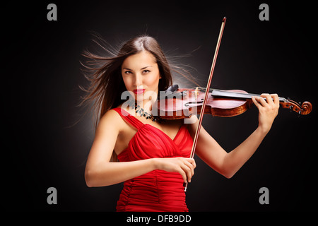 Jeune femme en robe rouge à jouer du violon Banque D'Images