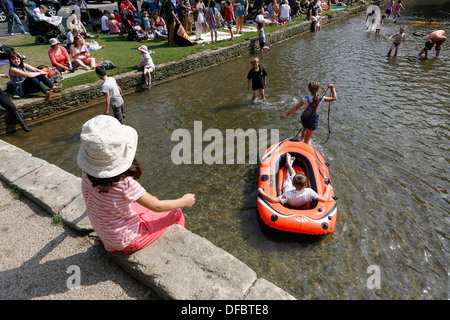 UK,Bourton-on-the-Water:personnes jouent dans la rivière Windrush. Bourton est une destination touristique populaire dans la région des Cotswolds. Banque D'Images