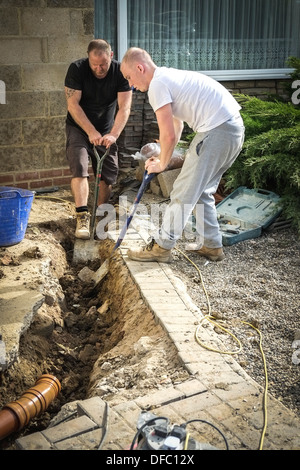 Deux constructeurs de creuser une tranchée en préparation à la pose de nouveaux tuyaux de drainage. Banque D'Images