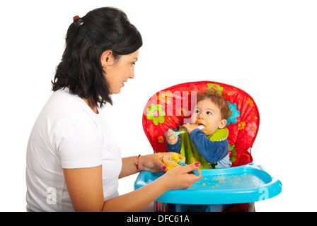 Mère de donner à son bébé purée de garçon et avoir conversation against white background Banque D'Images