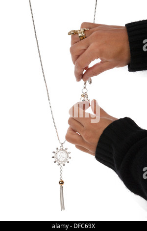 La main de womans bijoux positionnement contre la chaîne d'arrière-plan blanc. Banque D'Images