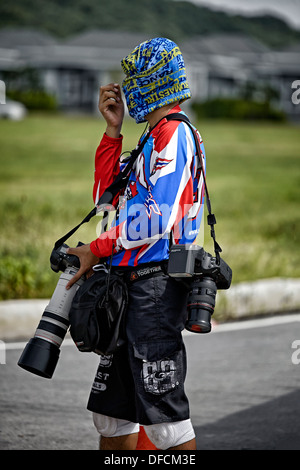 Attired coloré photographe professionnel prise de photos avec un assortiment de caméras et objectifs Canon. Banque D'Images