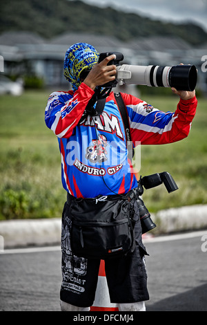 Attired coloré photographe de sport professionnel prise de photos avec un assortiment de caméras et objectifs Canon. Banque D'Images