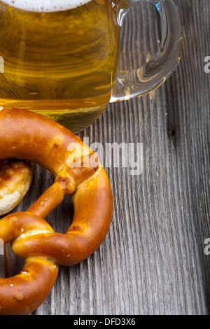 Une partie de d'un verre de bière et des bretzels sur une vieille table en bois rustique avec copie espace sur le côté droit Banque D'Images