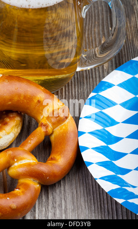 Une partie de d'un verre de bière, des bretzels et un document avec des plaques de losanges bleu et blanc sur une table en bois rustique Banque D'Images