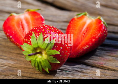 Fraises fraîches de la saison, l'un ensemble et deux demi sur un fond de bois Banque D'Images