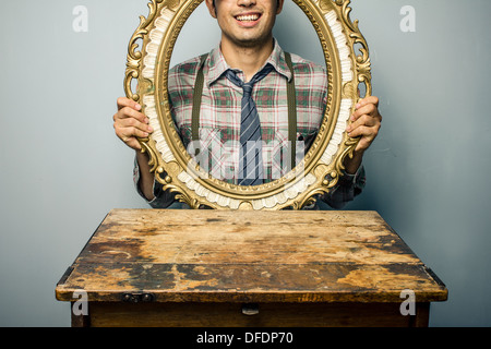 Jeune homme à l'intermédiaire d'un cadre photo vide Banque D'Images