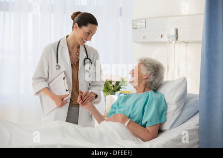 Médecin et senior patient in hospital room parler Banque D'Images