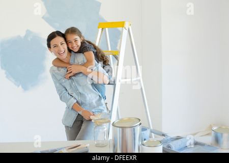 Portrait of mother and daughter hugging près de fournitures de peinture Banque D'Images