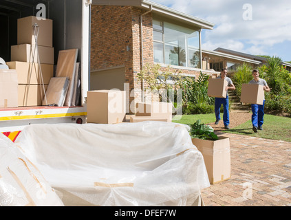 Movers carrying cardboard boxes de maison en camion de déménagement Banque D'Images