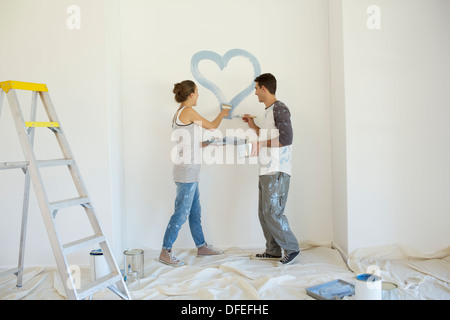 Couple painting blue heart on wall Banque D'Images