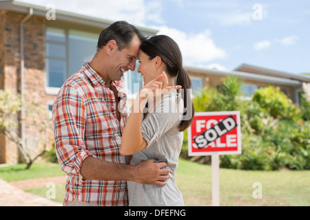 Couple hugging outside new house Banque D'Images