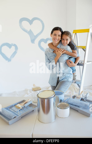 Mother and Daughter hugging parmi les fournitures de peinture Banque D'Images