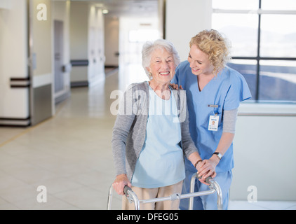 Nurse helping senior patient avec walker in hospital corridor Banque D'Images