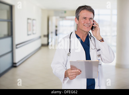 Doctor talking on cell phone in hospital corridor Banque D'Images