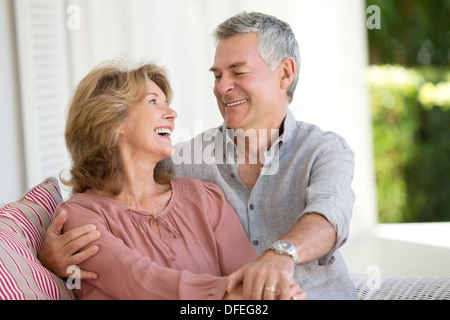 Senior couple hugging in armchair on patio Banque D'Images