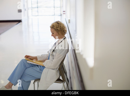 Médecin de l'examen medical chart in hospital corridor Banque D'Images
