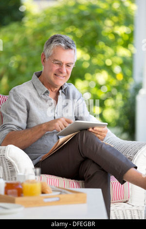 Senior man using digital tablet on patio Banque D'Images