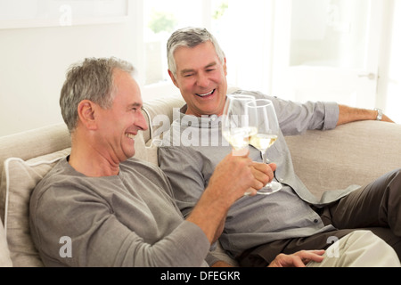 Senior men toasting wine glasses on sofa Banque D'Images