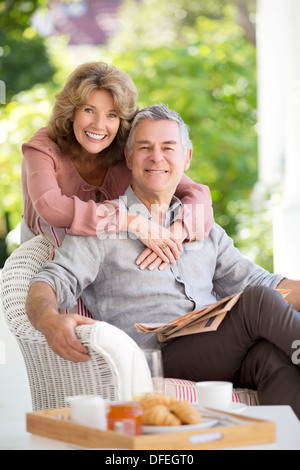 Portrait of smiling senior couple hugging on patio Banque D'Images