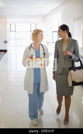 Médecin et businesswoman walking in hospital corridor Banque D'Images