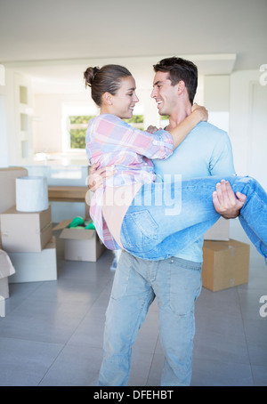 Man carrying girlfriend in new house Banque D'Images