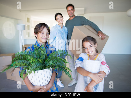 Portrait of smiling family holding possessions dans nouvelle maison Banque D'Images