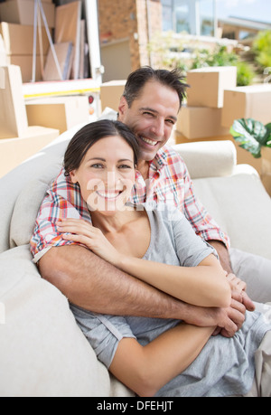 Portrait of smiling couple sitting on sofa in driveway près de camion de déménagement Banque D'Images