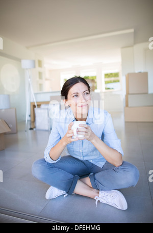 Happy woman enjoying coffee parmi les boîtes de carton Banque D'Images