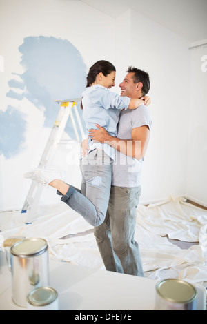 Couple hugging parmi les fournitures de peinture Banque D'Images