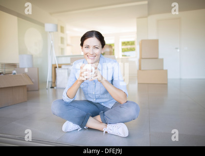 Femme buvant du café entre les boîtes de carton Banque D'Images