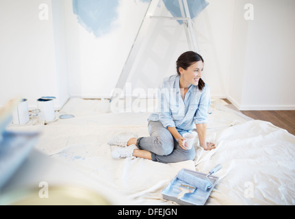 Femme buvant du café entouré de fournitures de peinture Banque D'Images