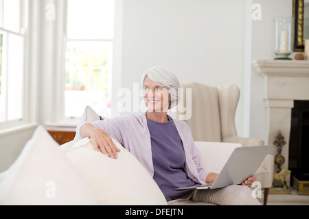 Senior woman using laptop on sofa Banque D'Images