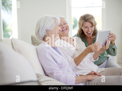 Les femmes plus âgées using digital tablet on sofa Banque D'Images