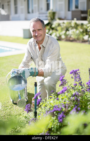 Senior man watering plants in garden Banque D'Images