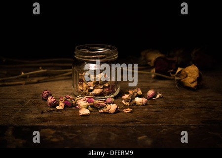 Bocal en verre avec boutons de rose séchés et dead roses dans l'arrière-plan Banque D'Images