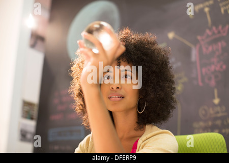 Businesswoman examinant crystal ball in office Banque D'Images