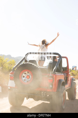 Woman cheering dans un véhicule utilitaire sport sur route de terre Banque D'Images