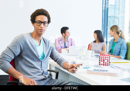 Businessman using cell phone in meeting Banque D'Images