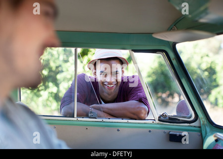 Smiling man leaning on fenêtre camping-car Banque D'Images