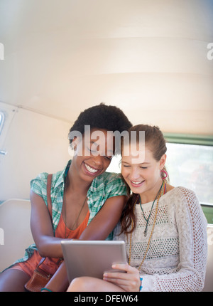 Women using digital tablet in back seat of camper van Banque D'Images