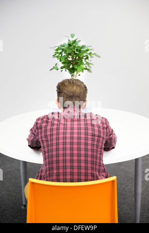 Businessman working at table with plant Banque D'Images